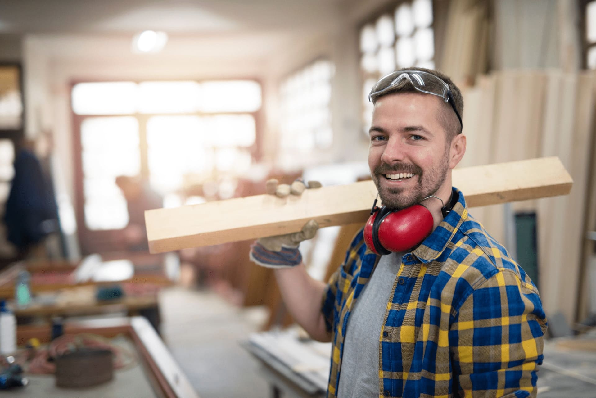 Lächelnder Handwerker trägt Holz und freut sich über ein passendes Monteurzimmer in Stralsund